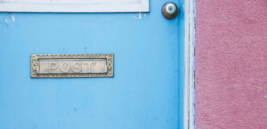 Closeup of a door with a mail slot with Post written on it.