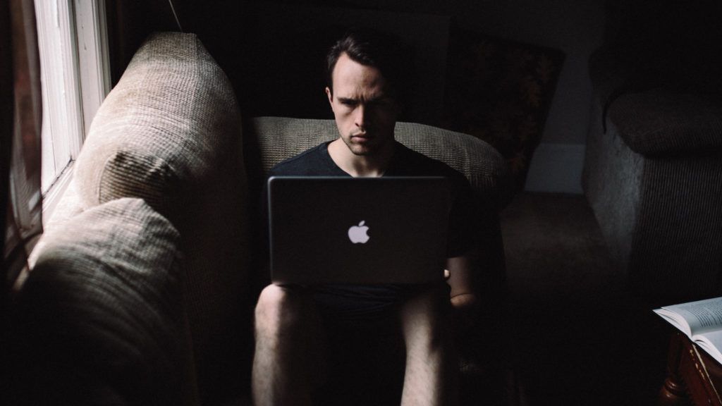 Man sitting on couch working on computer